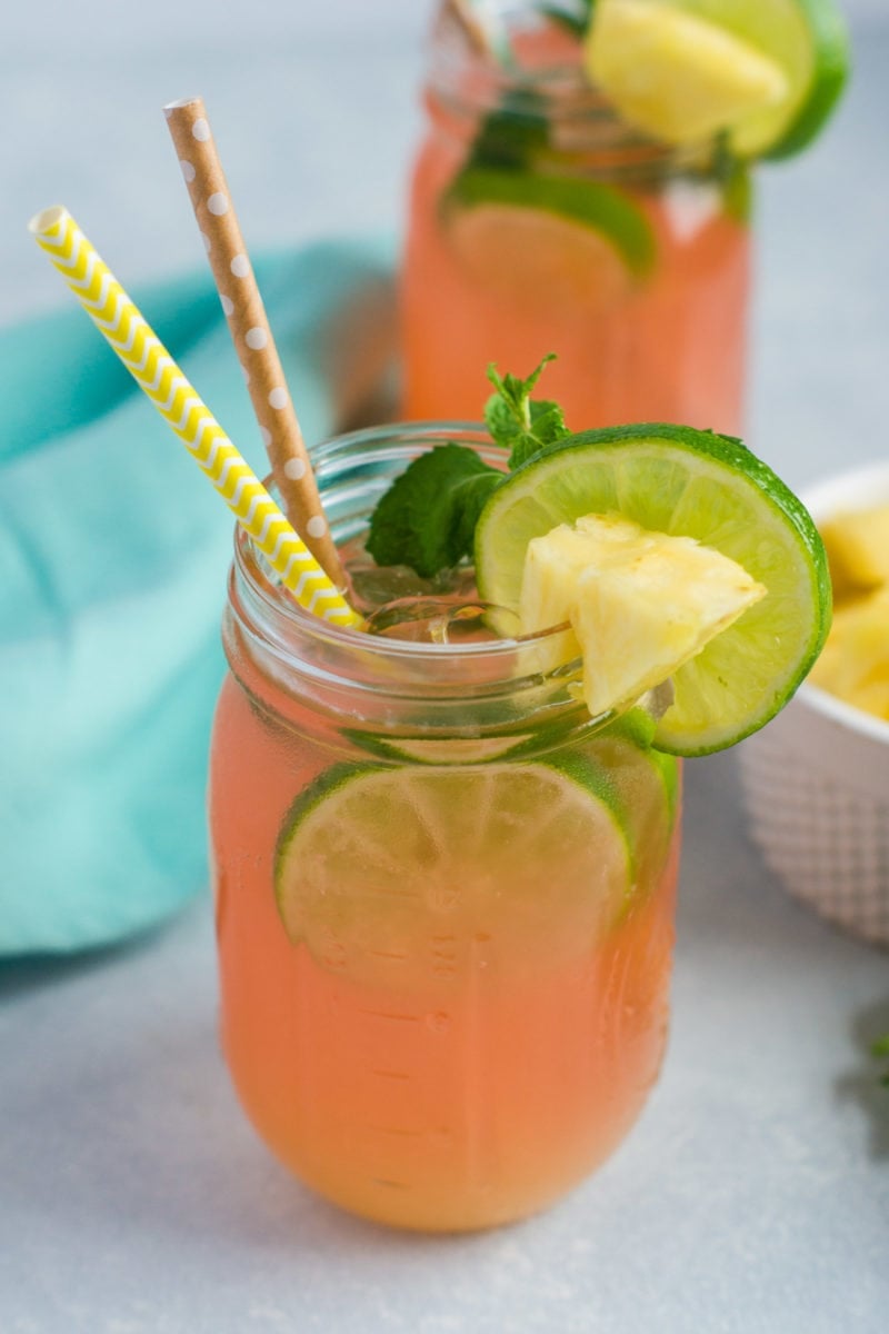 A cherry pineapple mojito in a glass mason jar with fresh garnishes.