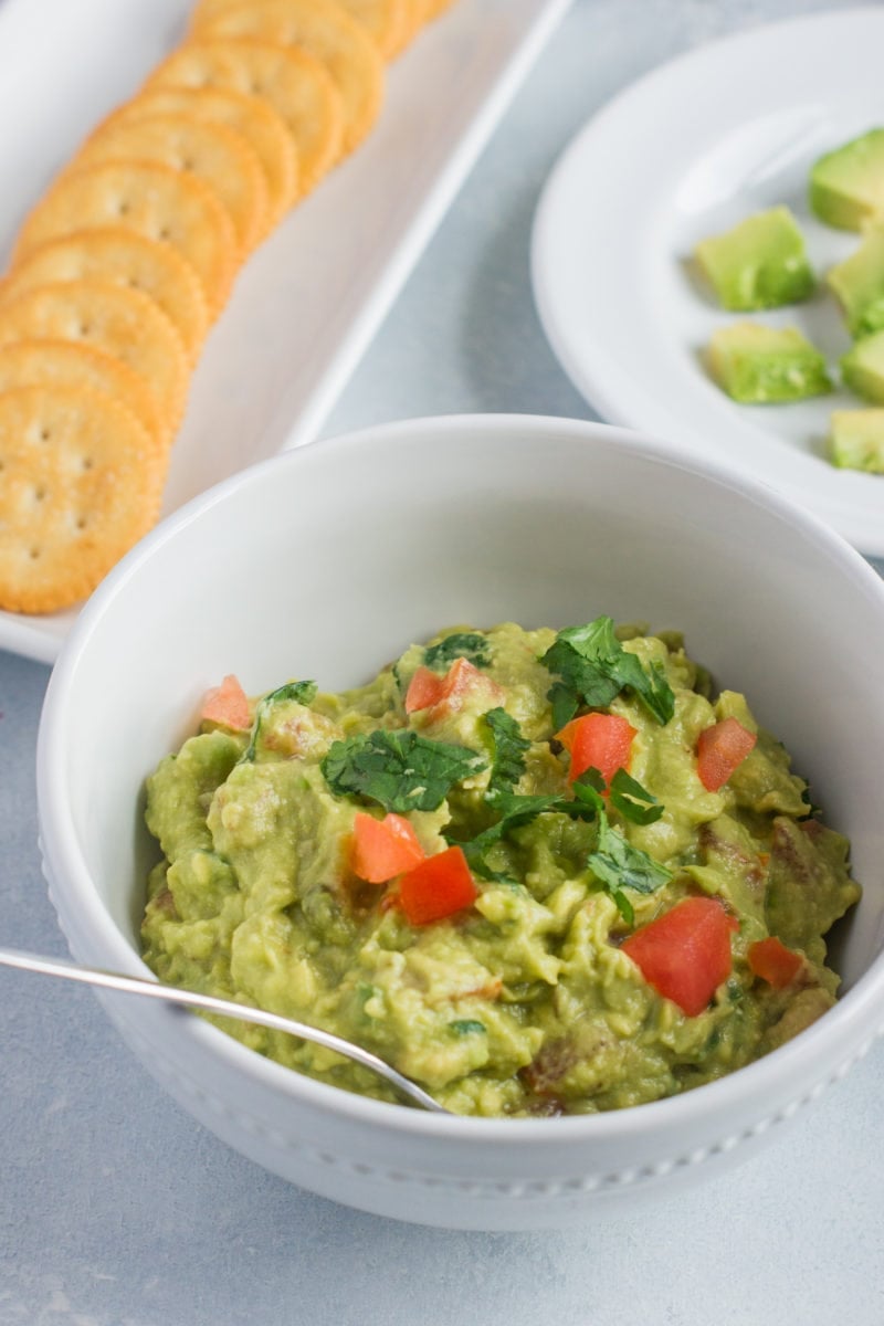 Close up of a bowl of homemade guacamole with a spoon in it.
