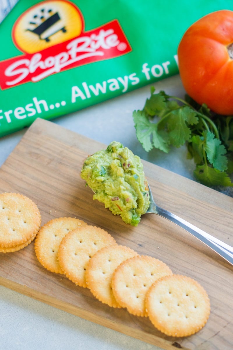 Ritz crackers next to a spoon of guacamole.