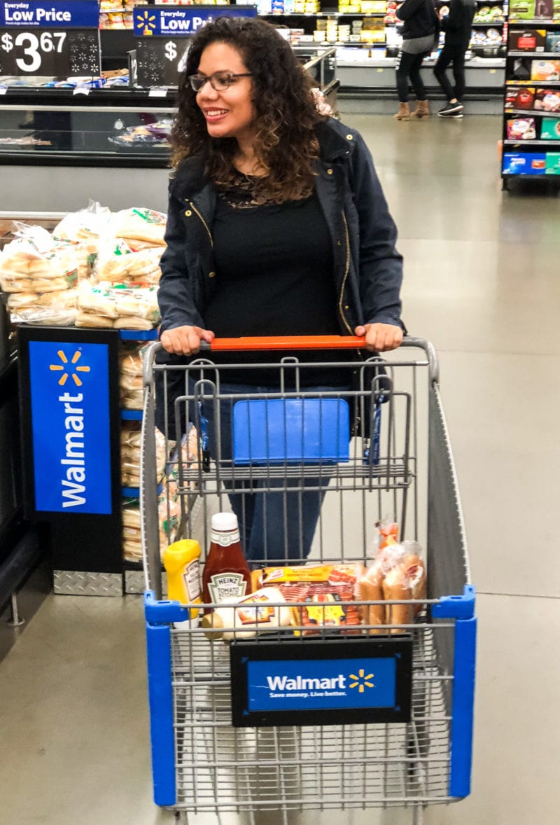 A woman pushing a Walmart shopping cart.