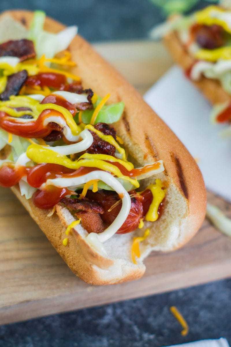 A close up of a hot dog in a bun covered in toppings.