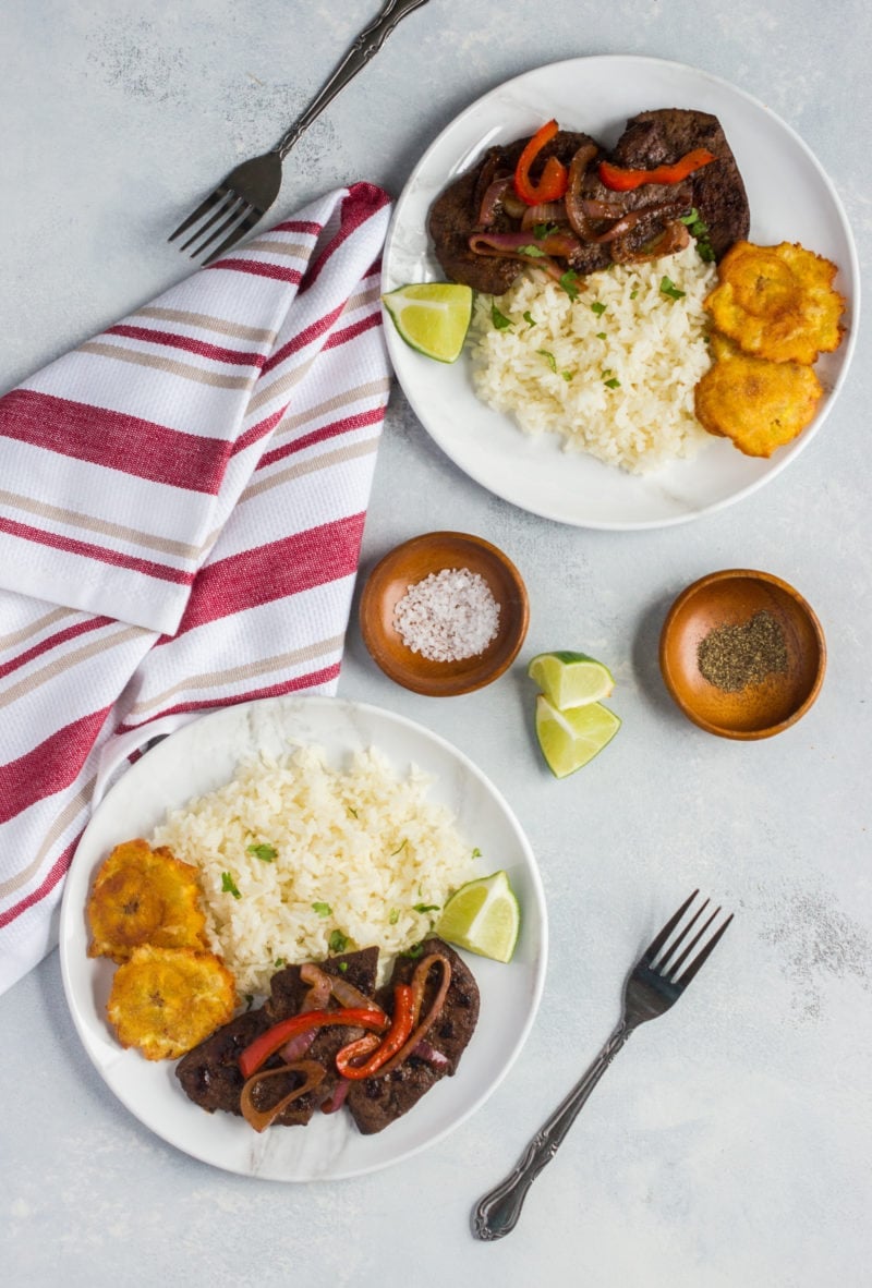 Liver and onions served on two white plates with rice.