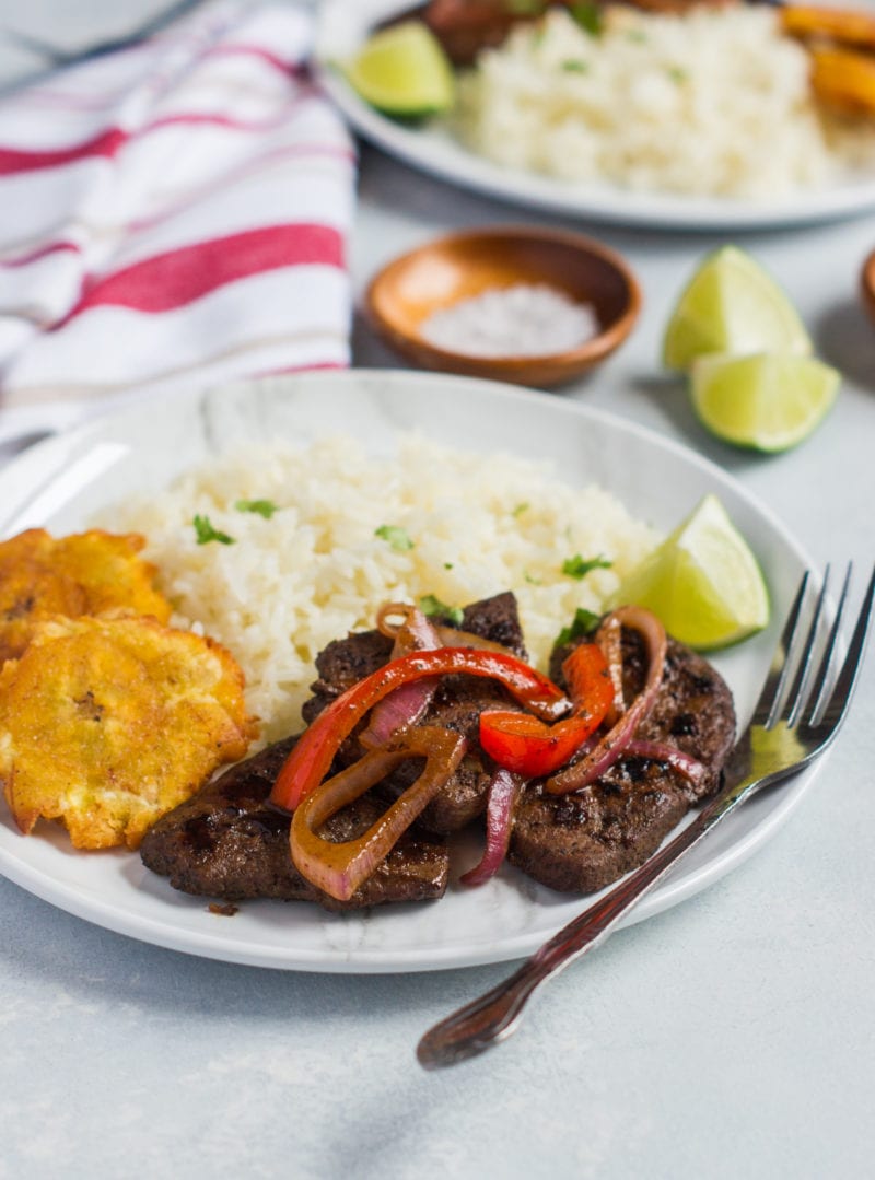 Liver and onions served with side dishes on a plate with a fork.