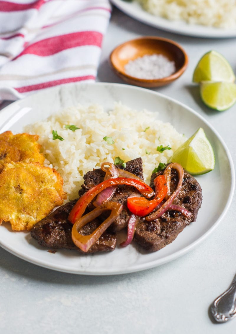 Higado encebollado served with rice on a plate.