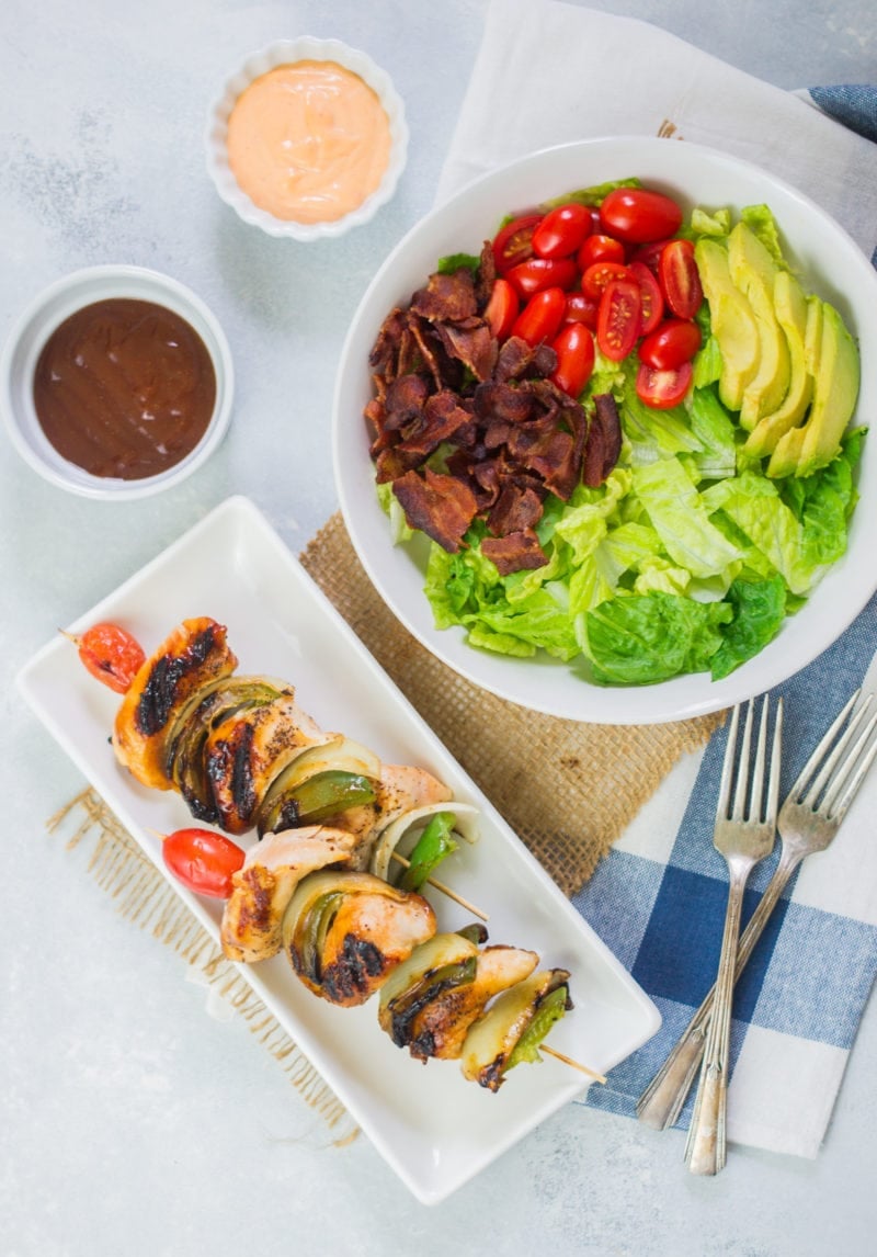 Overhead shot of chicken skewers and a salad bowl.