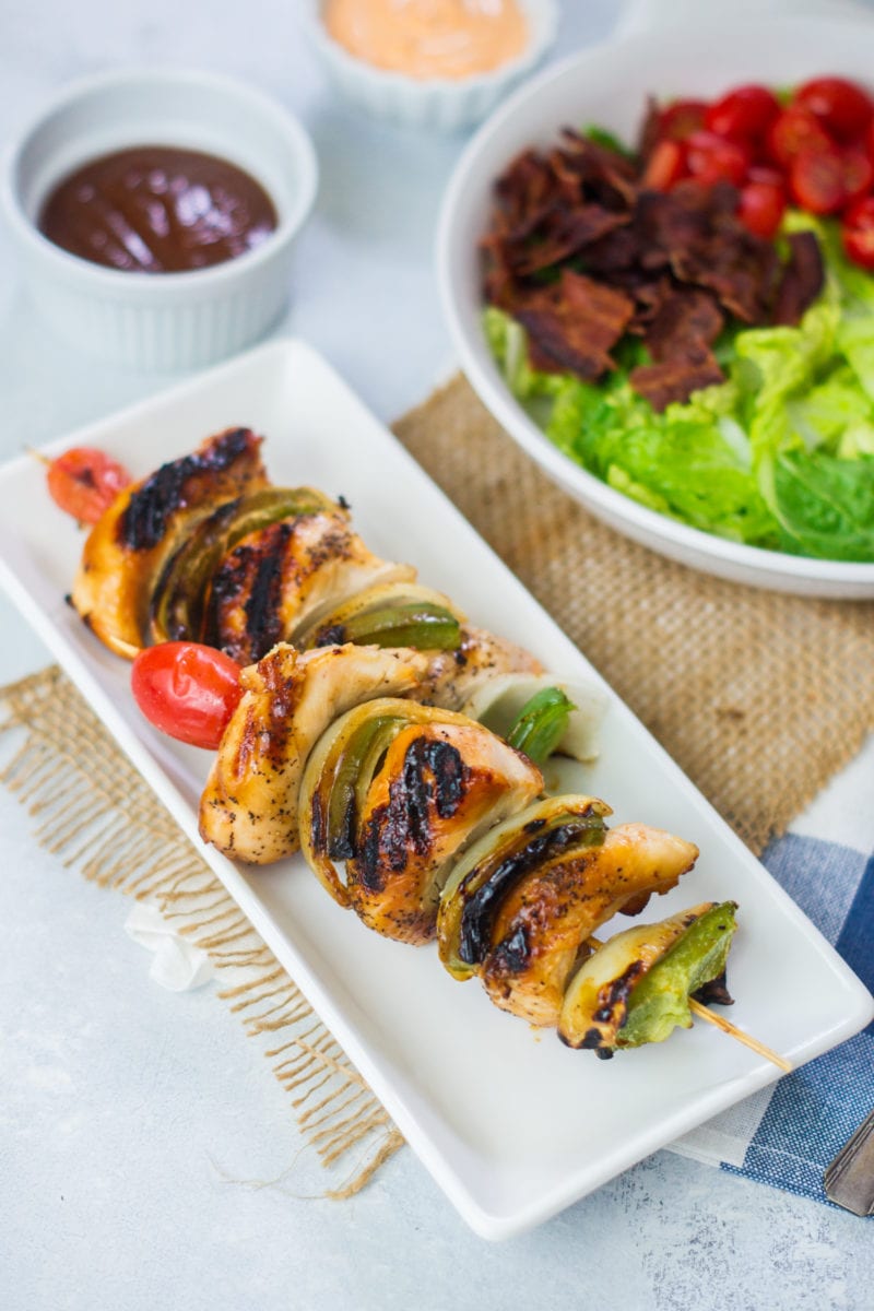 Two grilled chicken skewers on a long serving plate.