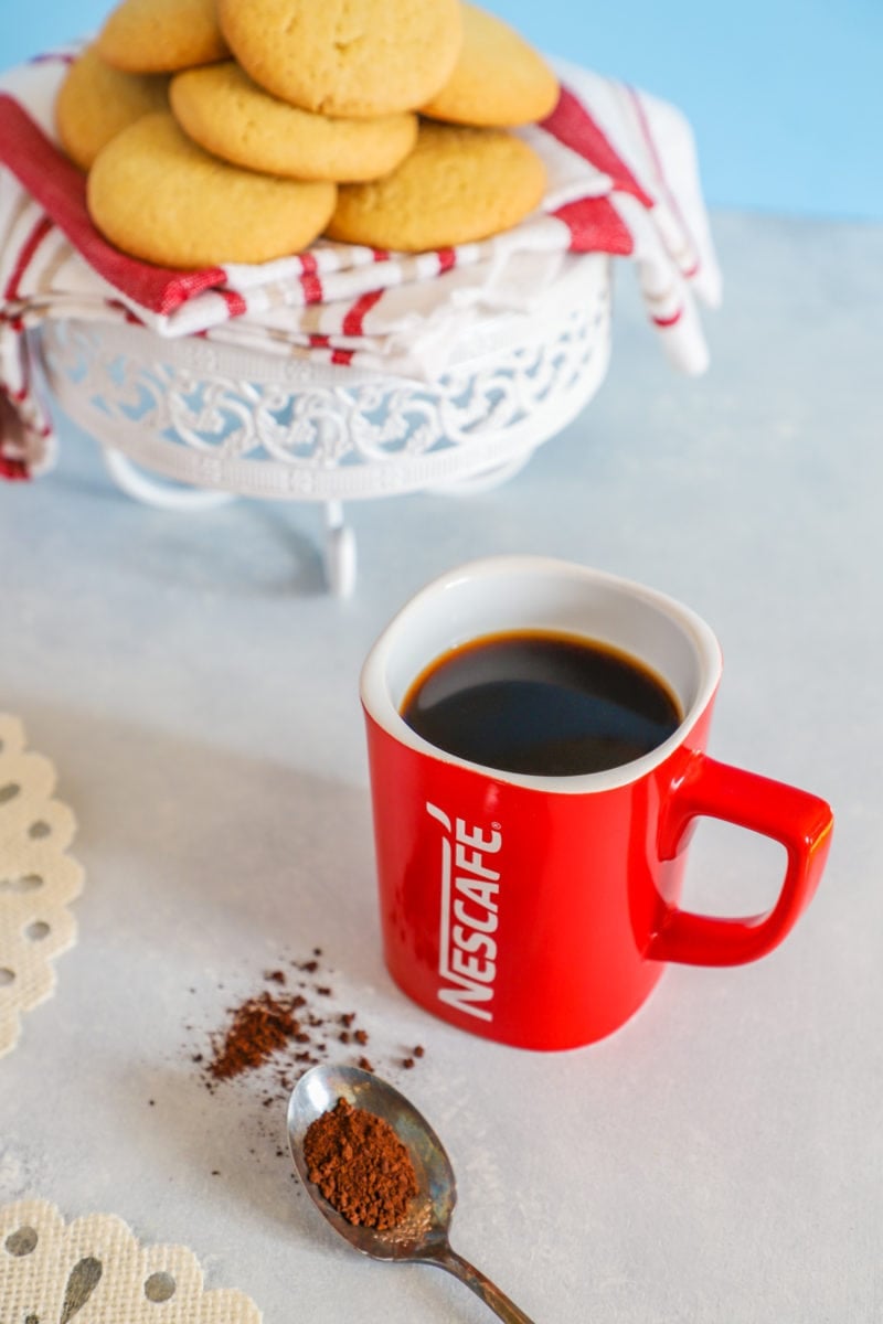 A cup of coffee next to some cookies.