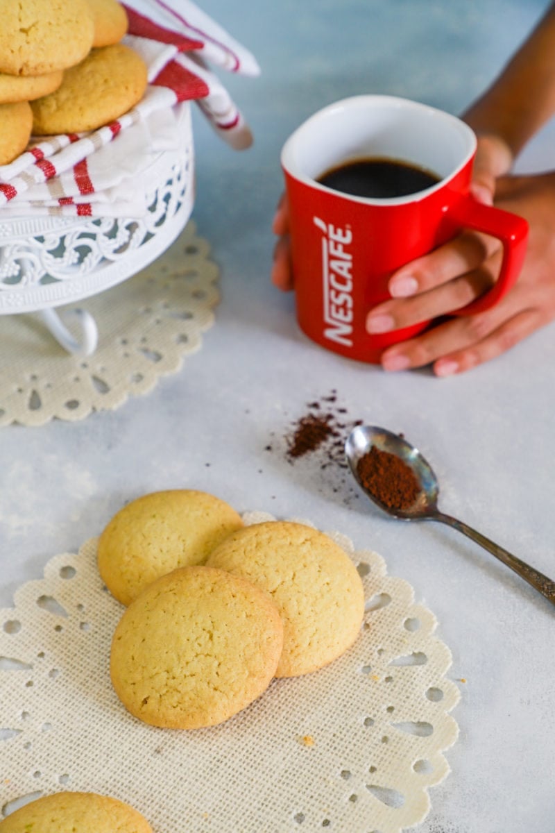 Butter cookies on a paper napkin next to a cup of coffee
