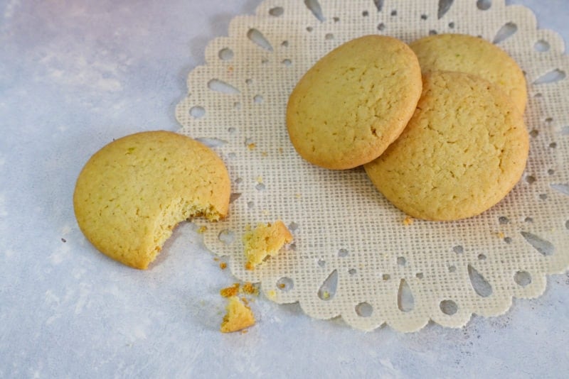 Four butter cookies with a bite taken out of one.