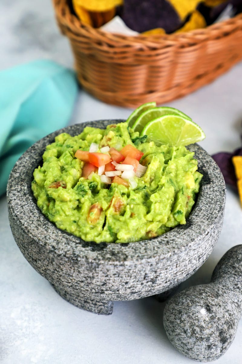 Homemade guacamole topped with fresh tomato and slices of lime.