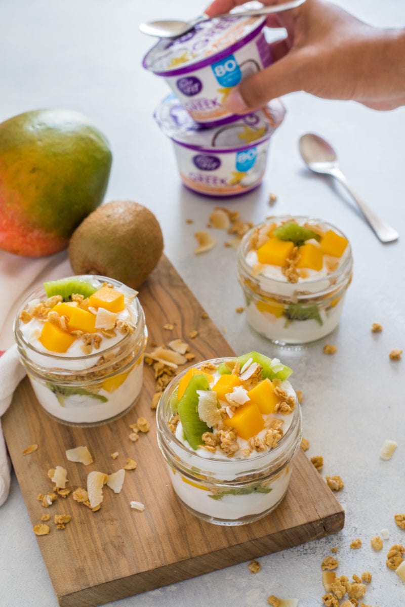 Three parfaits in glasses on a wooden chopping board.