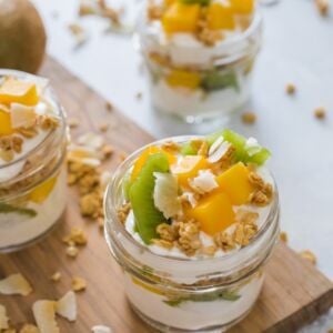 Tropical yogurt parfaits served in three glass jars.