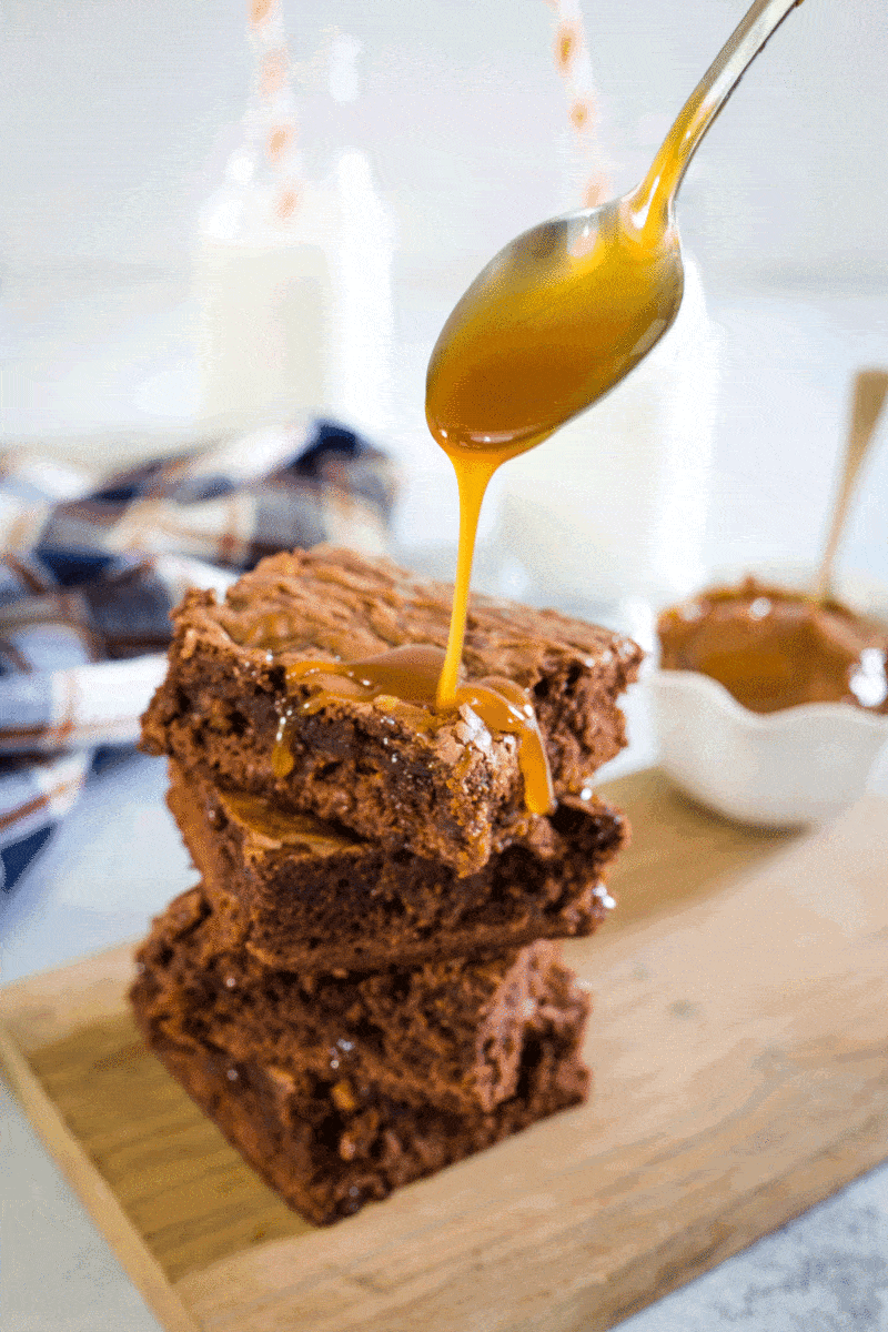 A stack of three brownies being drizzled with dulce de leche.