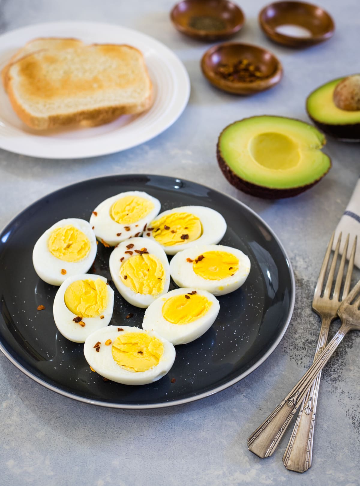 Hard boiled eggs on a black plate sprinkled with red pepper flakes