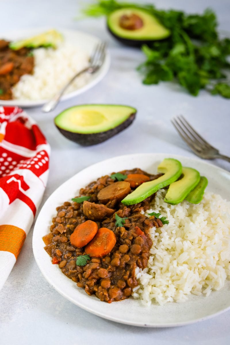 Lentil stew on a plate served with rice and avocado.