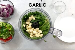adding herbs and garlic to food processor