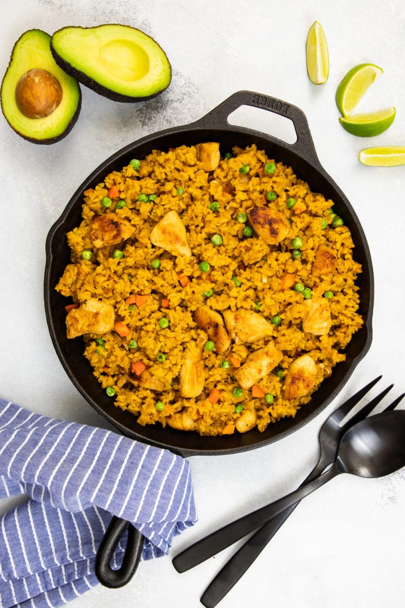 Chicken and Rice Mexican Style on a cast iron skillet with a side of avocado