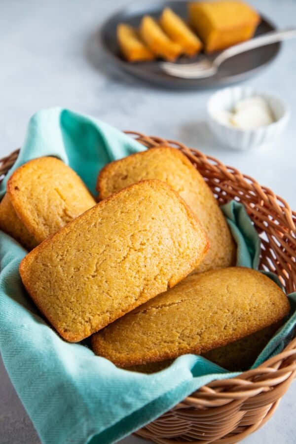 Four cornbread loaves in a basket with a blue cloth.