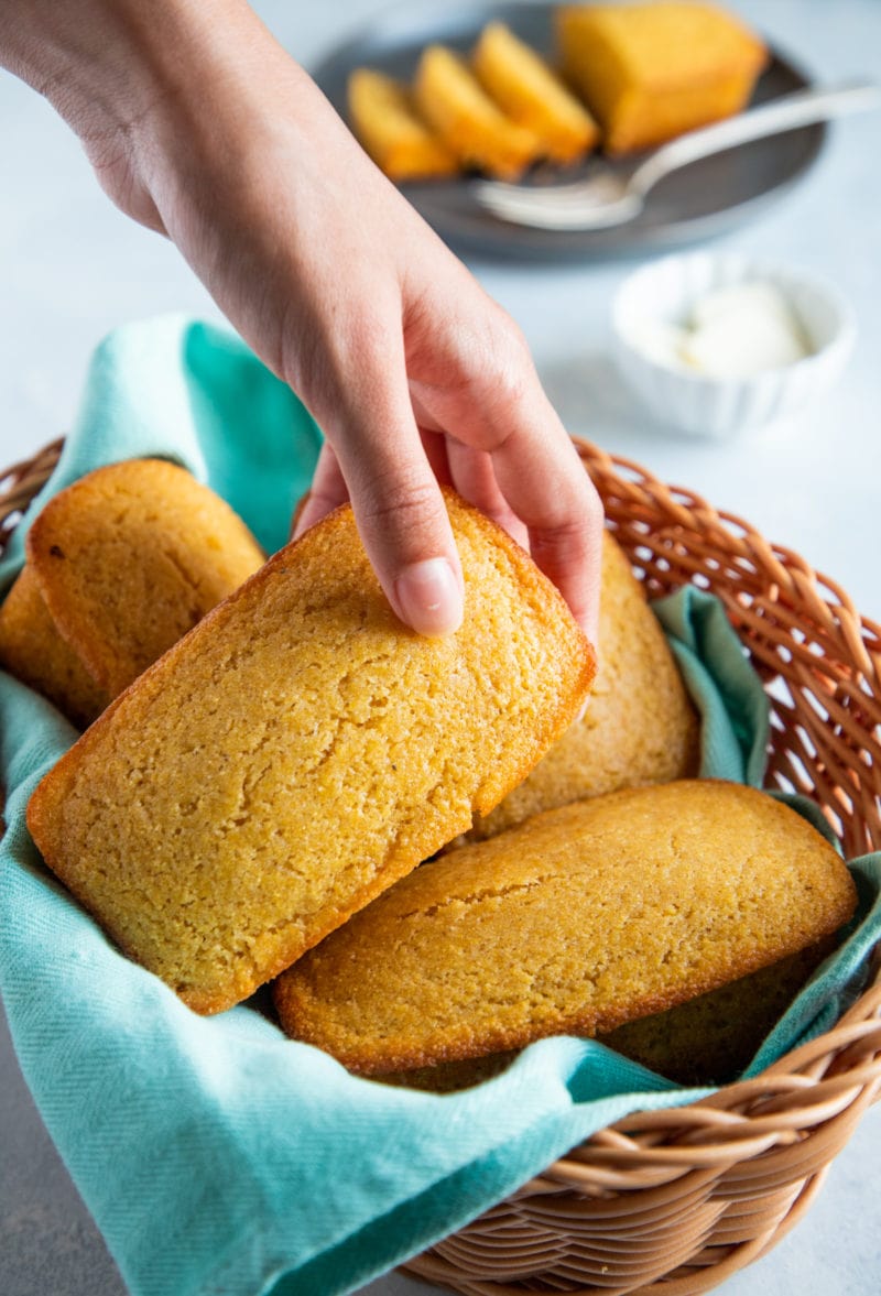 A cornbread loaf being picked up out of a basket.