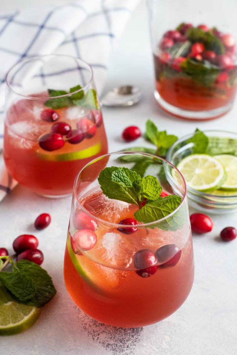Two glasses of cranberry mojito garnished with mint and fresh cranberries.