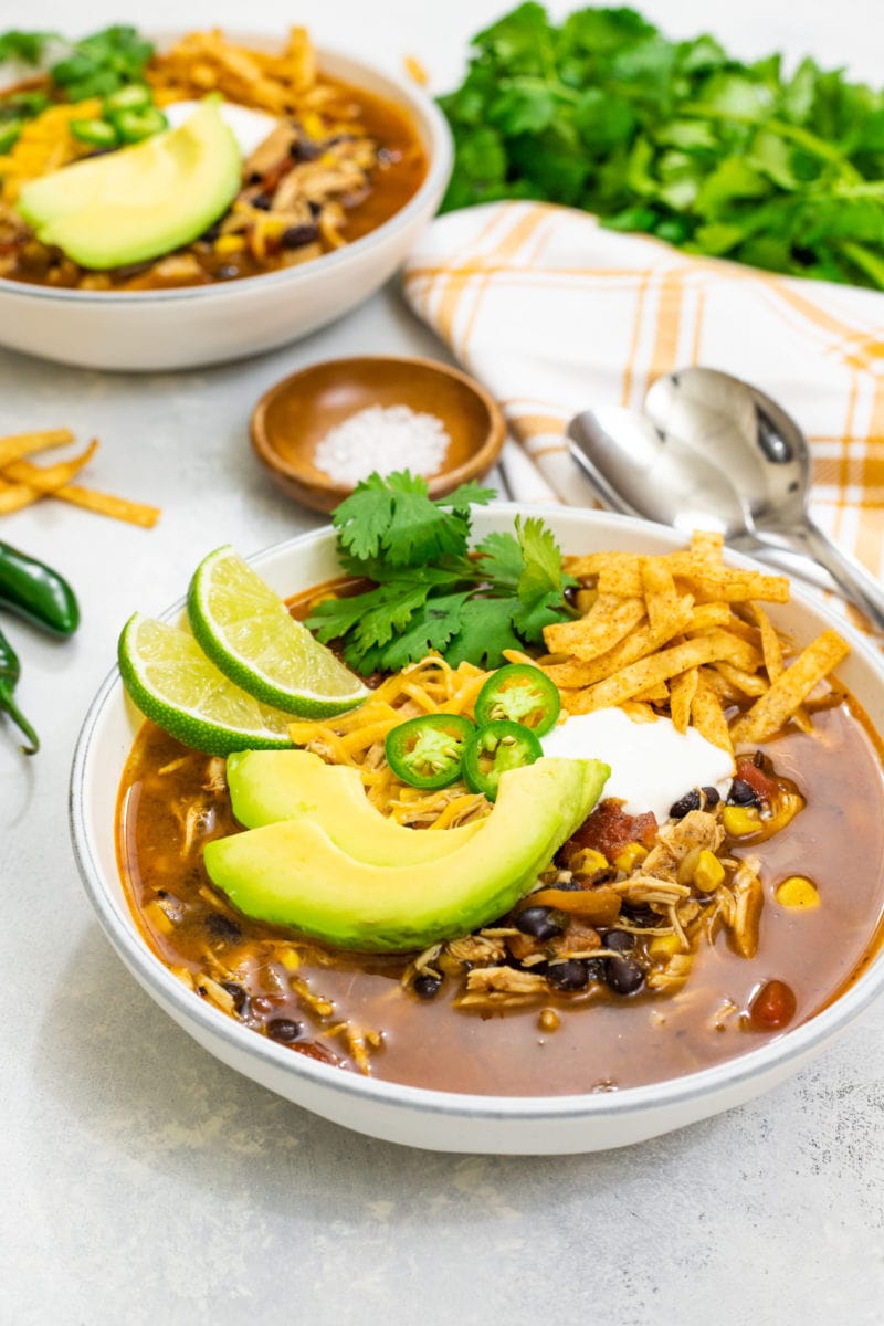 sopa de tortilla con pollo en un bowl servida con queso, limon y aguacate