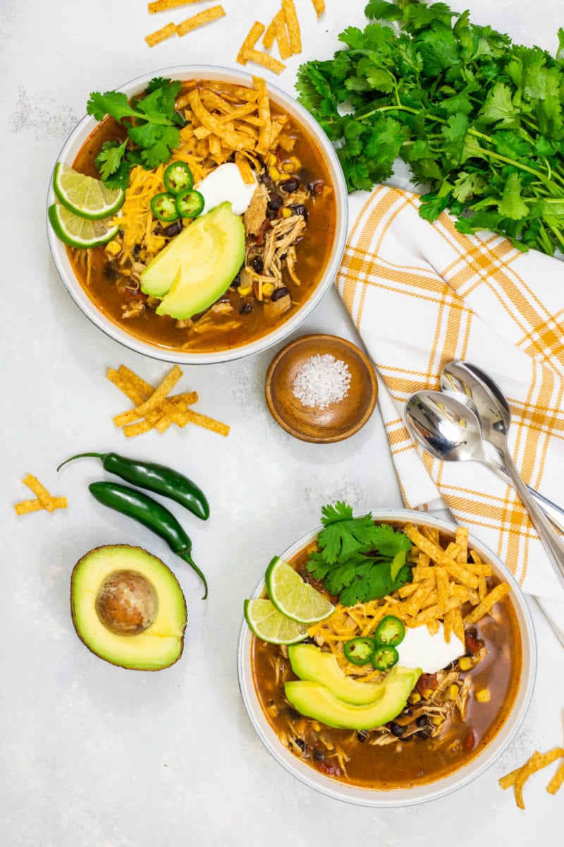 Chicken tortilla soup served in two white bowls with toppings.
