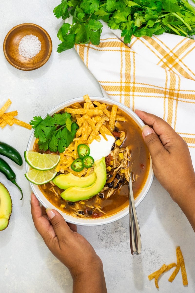 sopa de tortilla con pollo servida en un bowl con queso, limon y aguacate