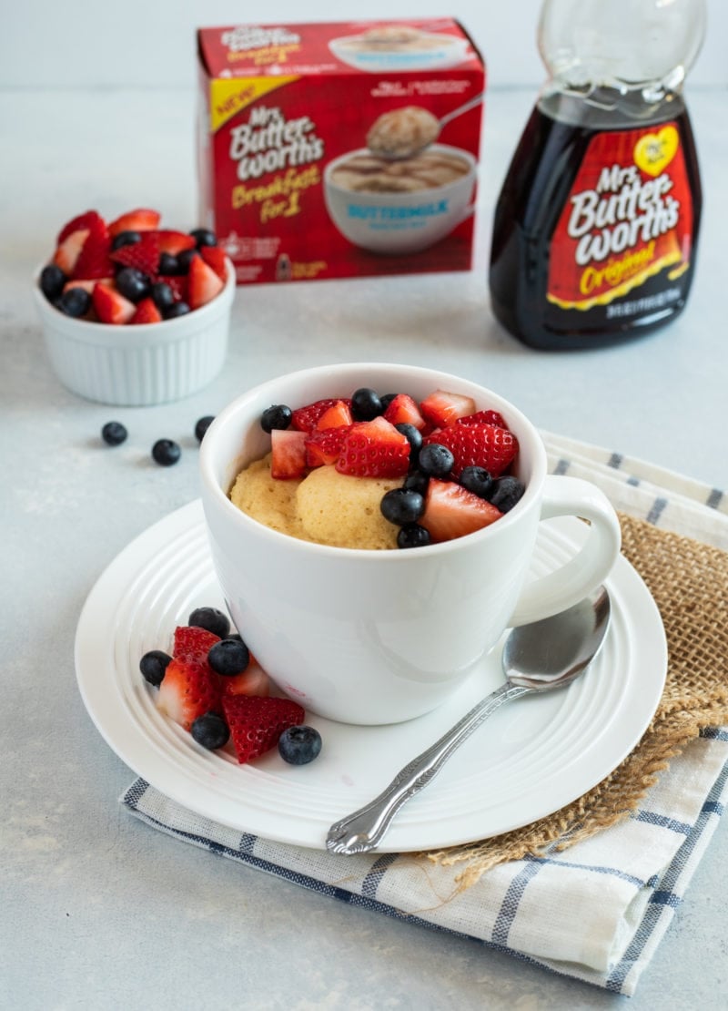 A pancake in a mug topped with fresh berries.