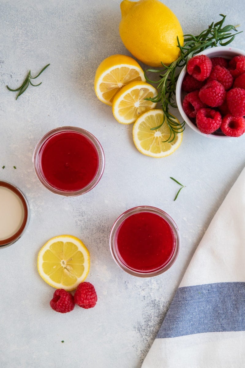 Overhead shot of two small jars of raspberry simple syrup.