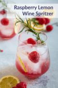 raspberry lemon wine spritzer served in a glass with lemon slices, raspberries and rosemary for garnish