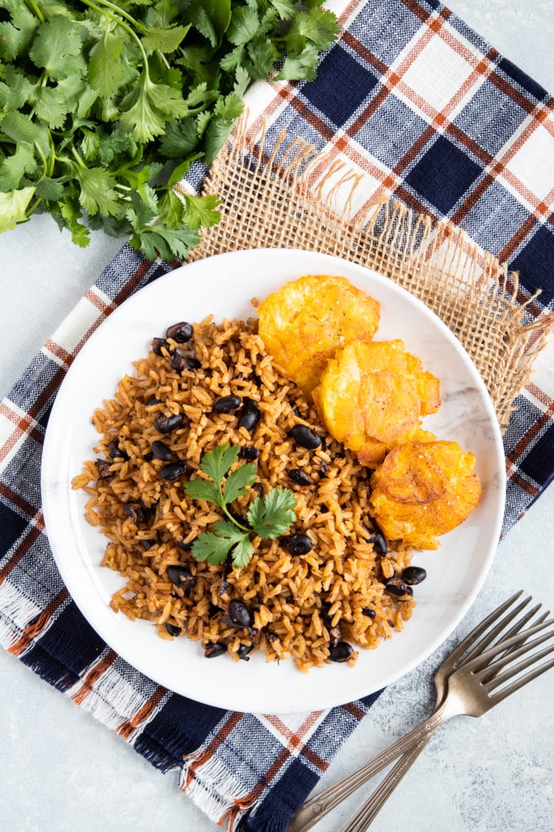 Overhead shot of black beans and rice (arroz congri) served on a white plate.