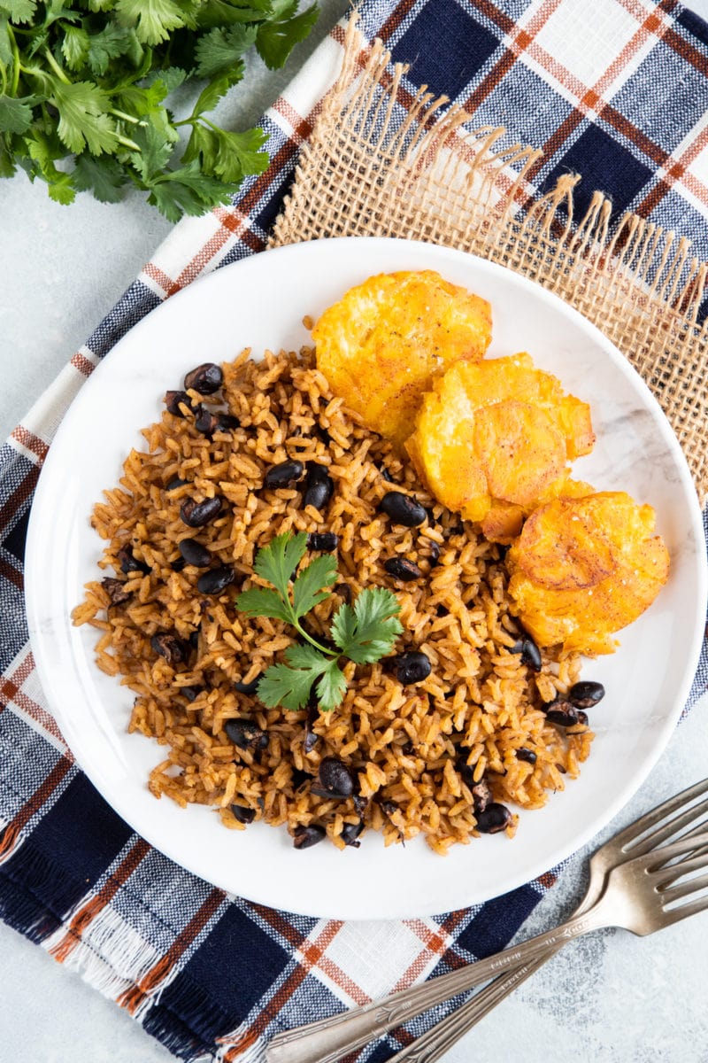 Black Beans and Rice aka arroz Congri served on a white plate with tostones on the side