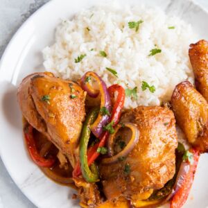 Close up of braised chicken and vegetables served next to white rice.
