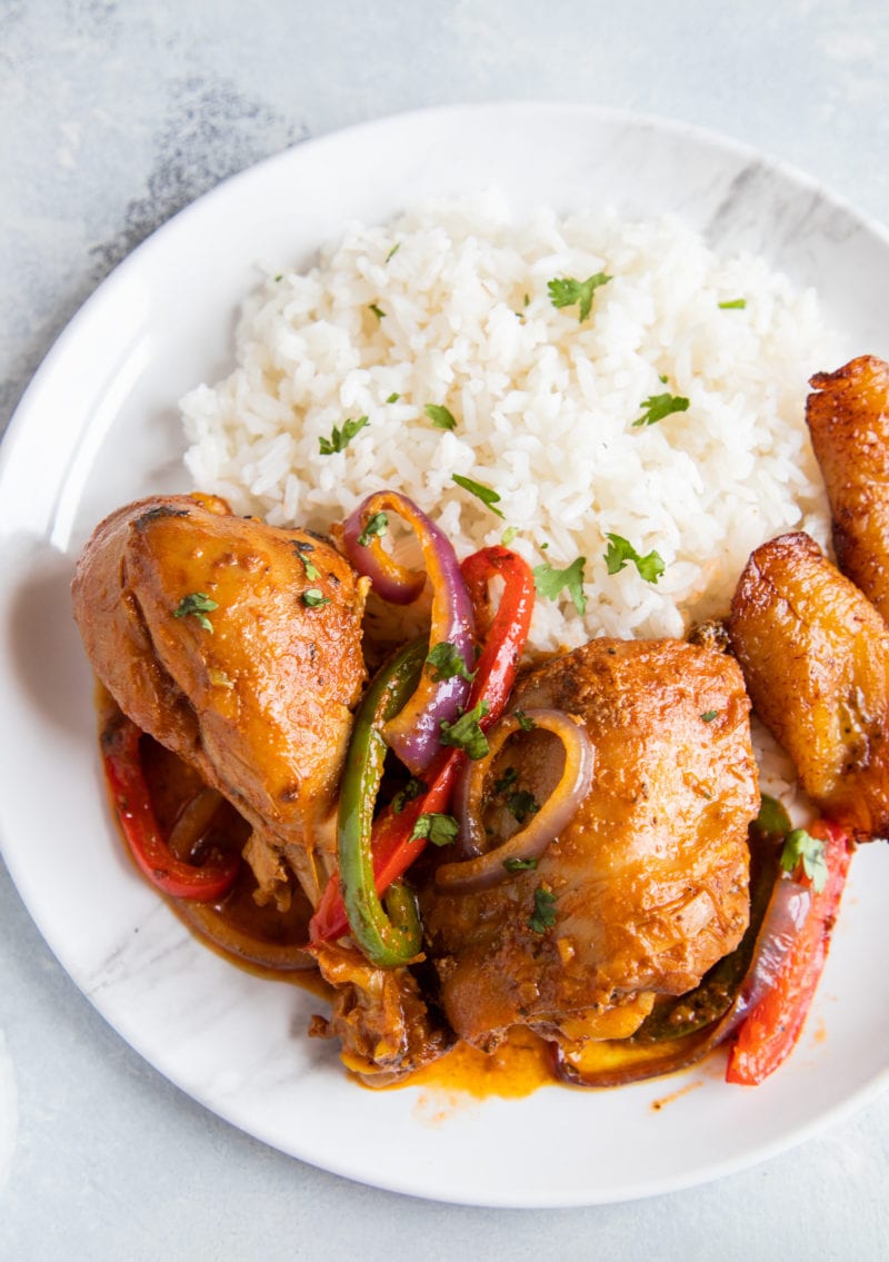 Pollo Guisado servido en un plato con arroz blanco, frijoles y maduros