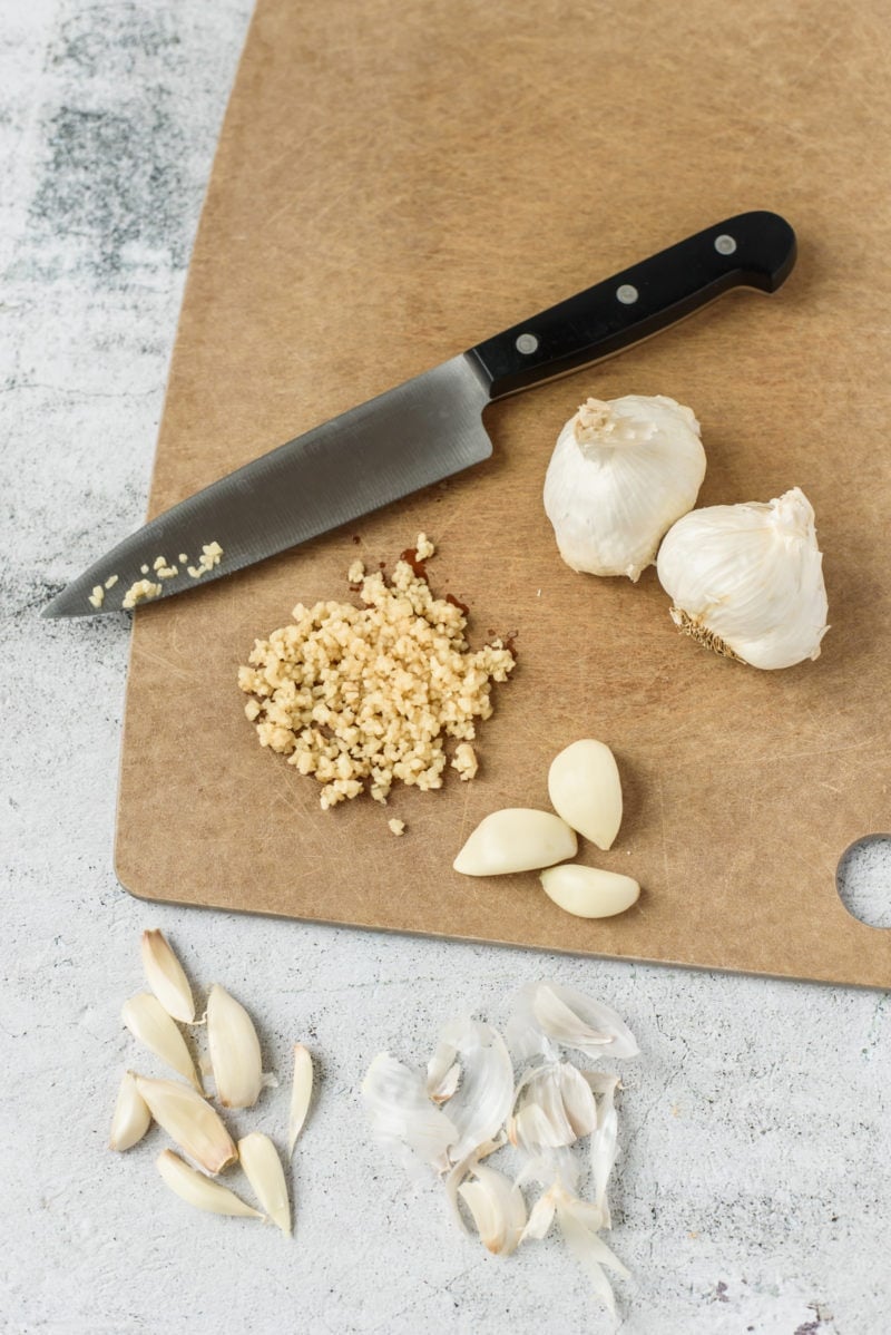Garlic bulbs, cloves and chopped garlic on a wooden board