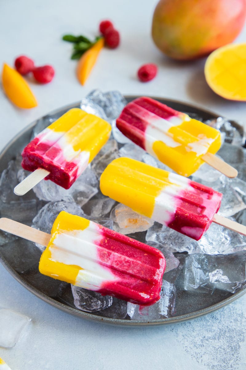 Mango Raspberry Yogurt Popsicles on a plate with ice