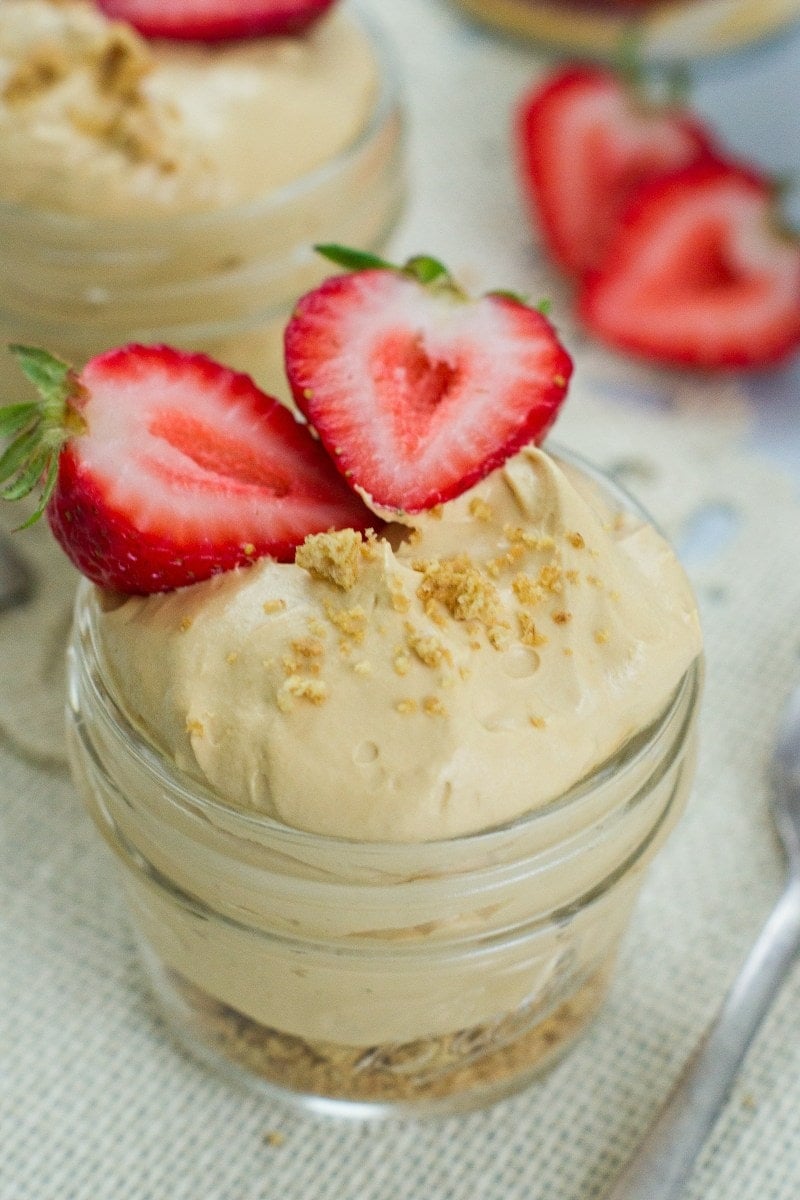 Dulce de leche cheesecake in a glass jar topped with a fresh strawberry.