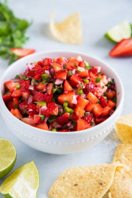 Fresh strawberry salsa in a white bowl next to tortilla chips.