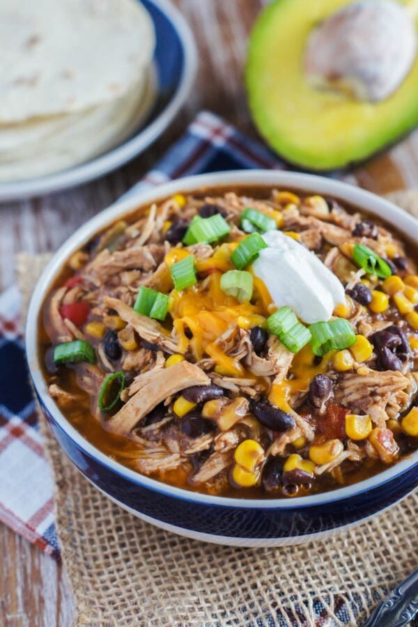 Slow cooker taco chicken chili in a blue and white bowl with toppings