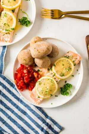 Foil baked salmon on a plate topped with slices of lemon