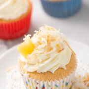 Coconut tres leches cupcake with whipped cream filling and topped with coconut flakes and pineapple