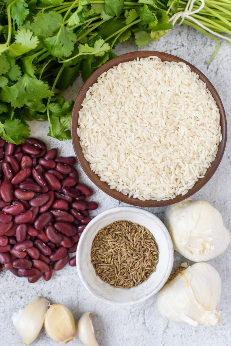 Elementos esenciales de la despensa: arroz, frijoles, cilantro, comino y ajo colocados en una pizarra blanca
