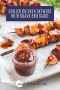 Guava BBQ Sauce in a jar with chicken skewers in the back Pinterest Image 3
