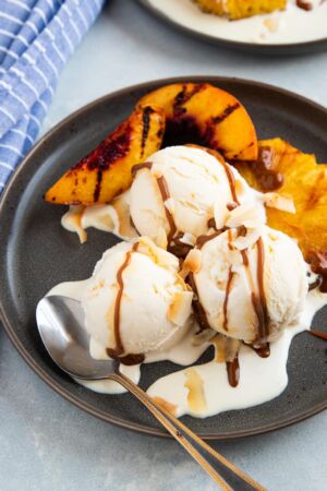 grilled pineapple and peaches with vanilla ice cream and dulce de leche on a grey plate