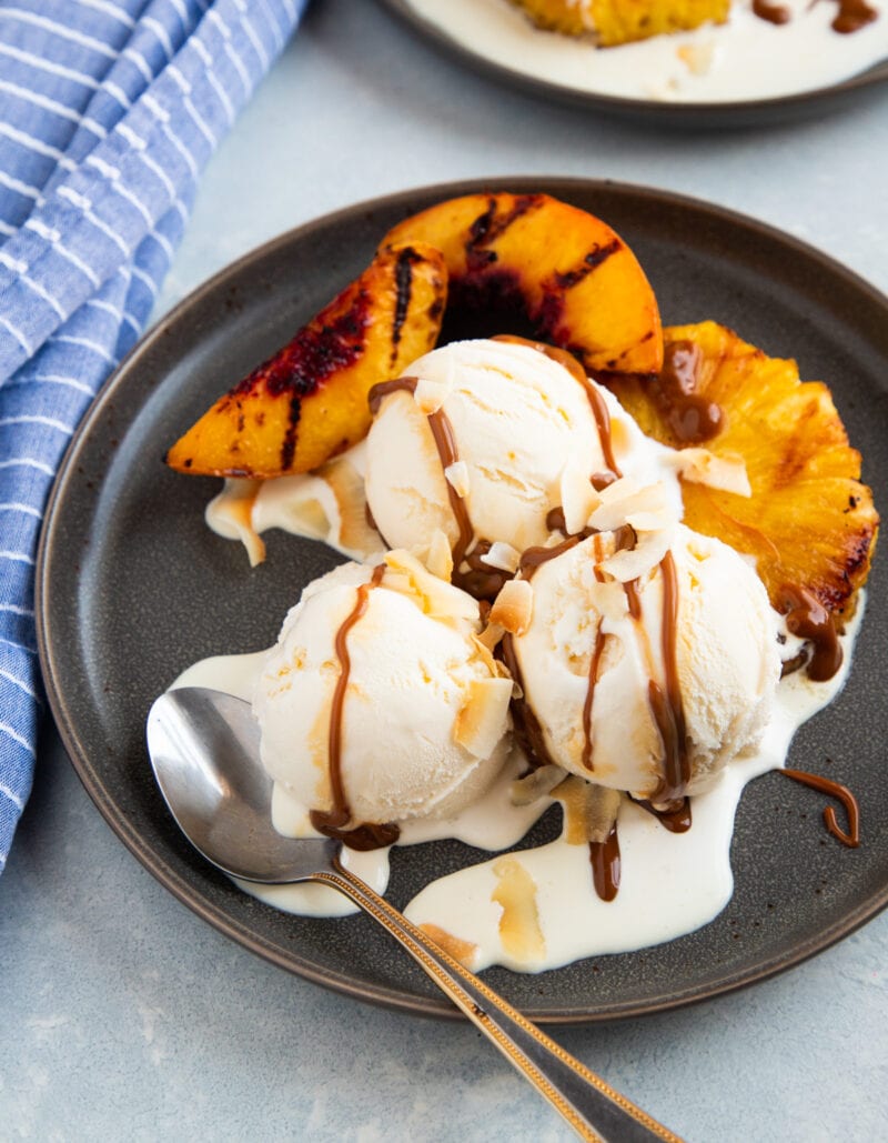 grilled pineapple and peaches with vanilla ice cream and dulce de leche on a grey plate