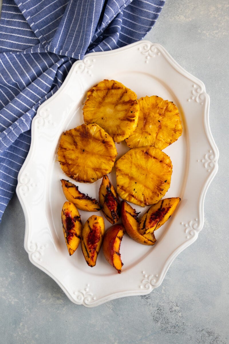 grilled pineapple and peaches on a white platter