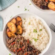 Shredded beef served in two bowls with rice and plantain