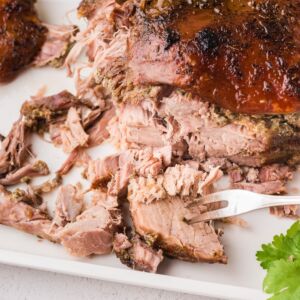 Pork roast cut into slices on a white plate and a fork in one piece.