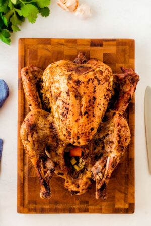 A whole mojo roasted turkey on a wooden chopping board.