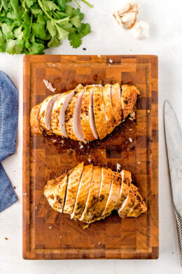 Two turkey breasts sliced on a chopping board.
